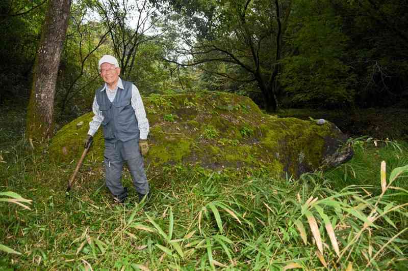 「亀石」周辺の草を払いながら笑顔を見せる田村四郎さん＝10月29日、山江村