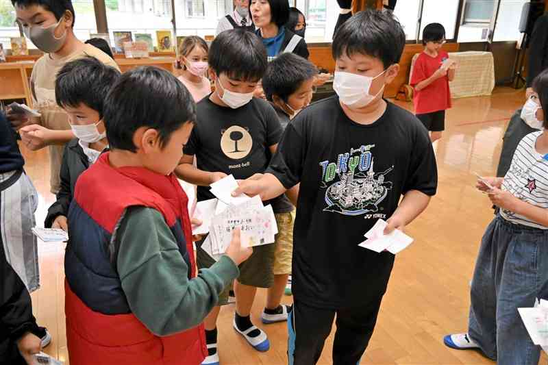 手作りの名刺を交換し合う中北小と久木野小の児童＝10月31日、南阿蘇村