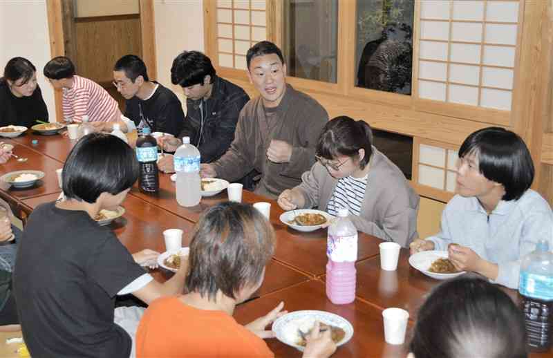 縁が輪の参加者と談笑しながら夕食を食べる住職の佐藤薫人さん（中央）＝10月27日、熊本市東区