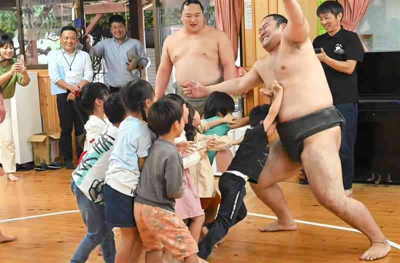 鳴戸部屋の力士と相撲を取る園児たち＝1日、山鹿市