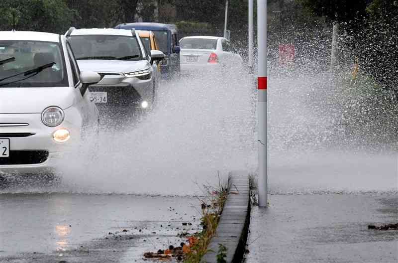 水しぶきを上げて走行する車両＝2日午前10時ごろ、合志市（谷川剛）