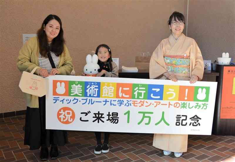 「美術館に行こう！」展で1万人目となった（左から）野﨑さん親子＝7日、熊本市中央区