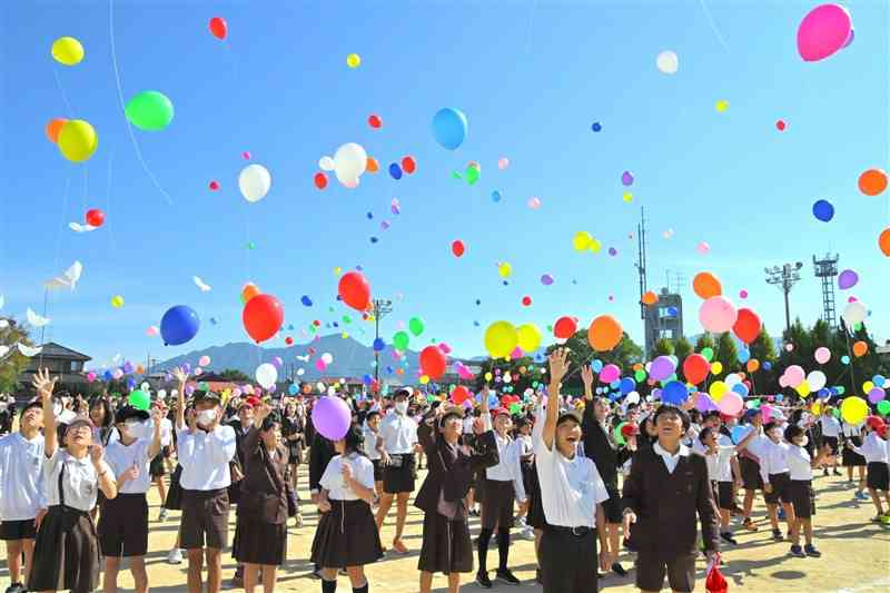 八千把小創立150周年記念式典で、風船を飛ばす児童ら＝8日、八代市