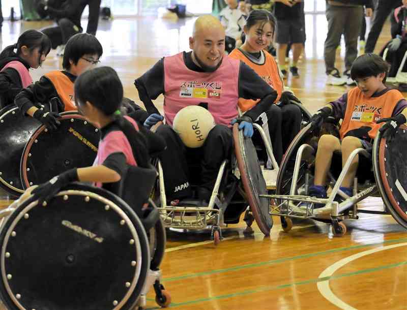 子どもたちに交じり、車いすラグビーをプレーする乗松聖矢選手（中央）＝9日、荒尾市