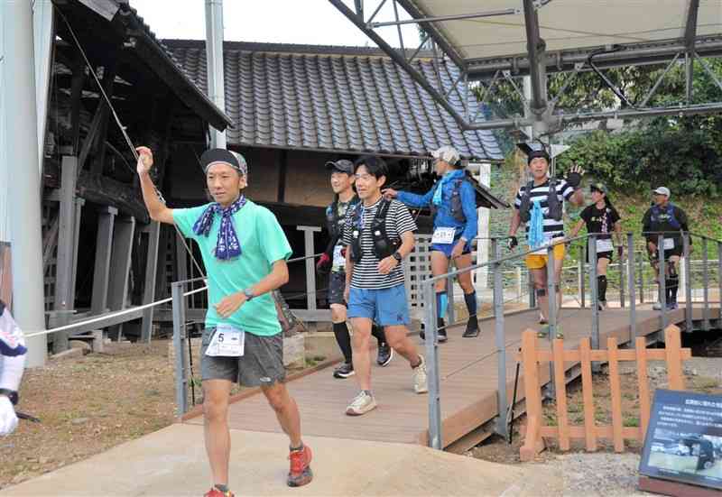 熊本地震で大きく傾いた納屋を見学しながら走る参加者＝9日、益城町