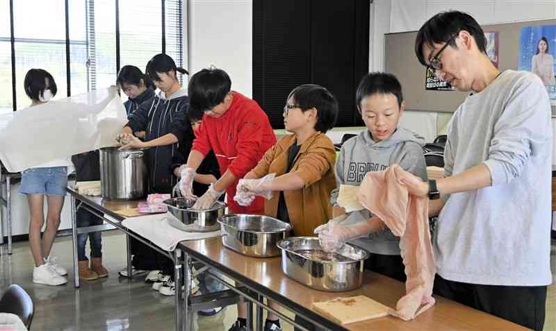 川原剛さん（右端）の指導を受け、天然染料で手拭いを染める小中学生＝9日、小国町