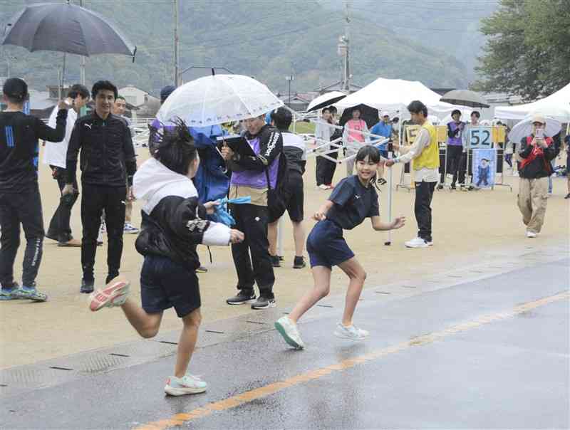 リレーマラソンでたすきをつなぐ佐敷中校区の子どもら＝10日、芦北町