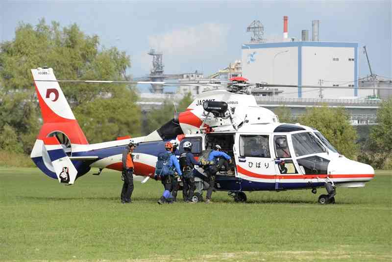 熊本県防災消防航空隊の防災消防ヘリコプターに乗り込む八代広域消防本部の山岳救助隊員ら＝12日、八代市