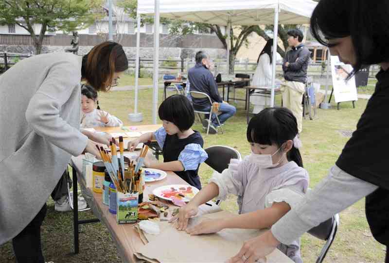 つなぎ美術館で展覧会を予定するアーティストの指導でアートを体験する子どもら＝9日、津奈木町