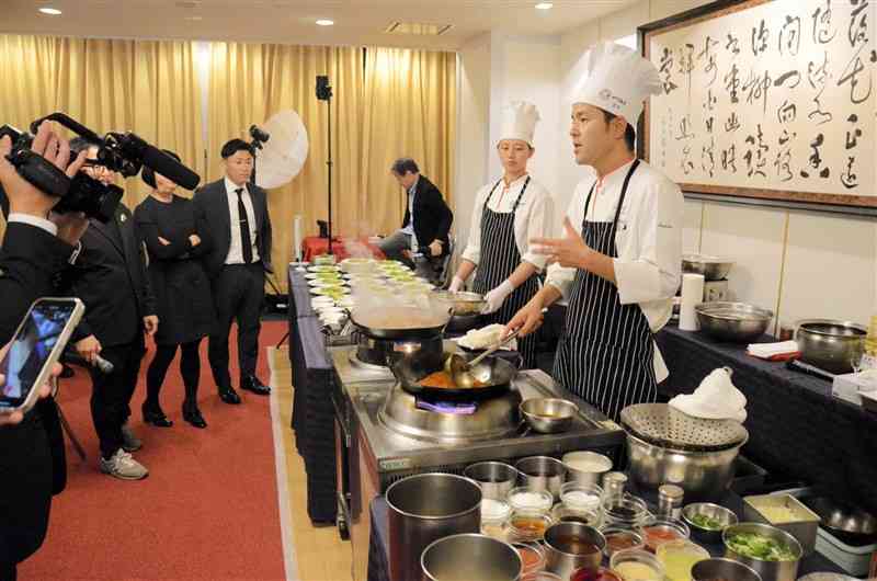 和水町産の食材の魅力を紹介しながら実演調理する赤坂四川飯店の宮本雅章副料理長（右）＝13日、東京・平河町