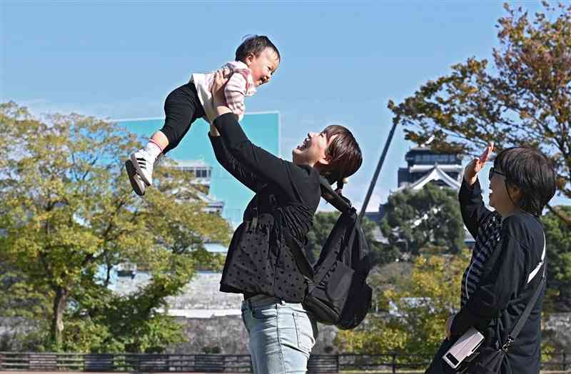 陽光の下、薄着姿でくつろぐ親子＝14日午後1時55分ごろ、熊本市中央区の熊本城二の丸広場（小野宏明）