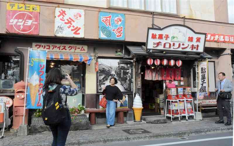 昭和レトロな店先で記念撮影する台湾の旅行関係者＝14日、阿蘇市