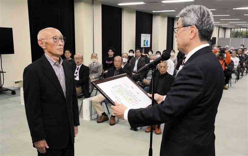 熊日の藤本雅士常務（右）から熊日賞の賞状を受ける若田利光さん＝16日、熊本市中央区