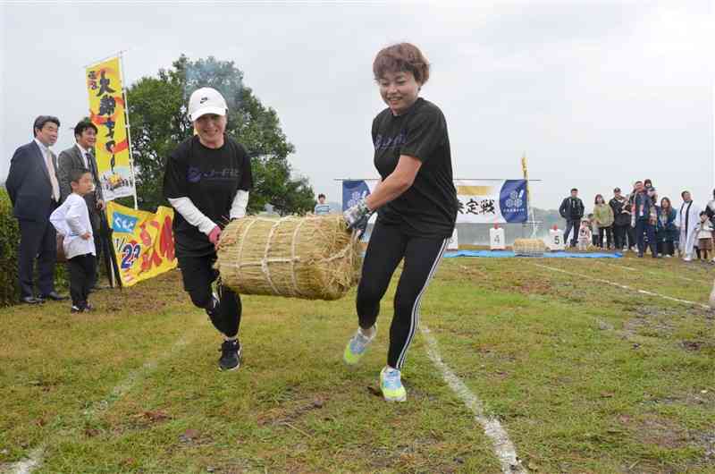 2人1組で米俵を運ぶ「米俵積出王決定戦」の参加者＝17日、玉名市