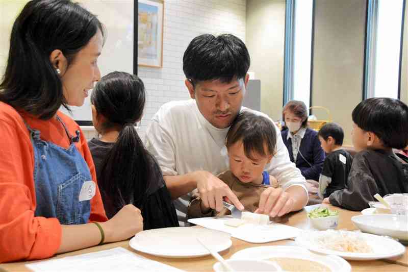 企業のカフェテリアで開かれた料理教室で野菜を切る親子＝17日、熊本市東区