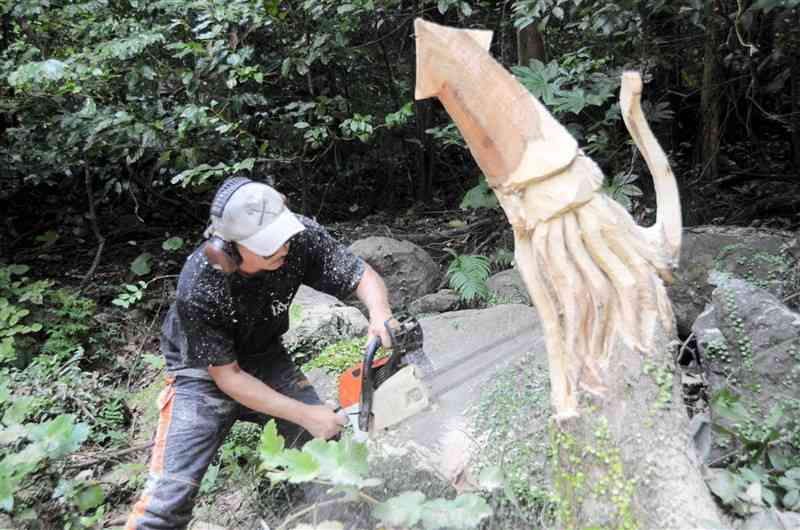 チェーンソーアートでイカのオブジェを制作する齋藤和紀さん＝16日、天草市