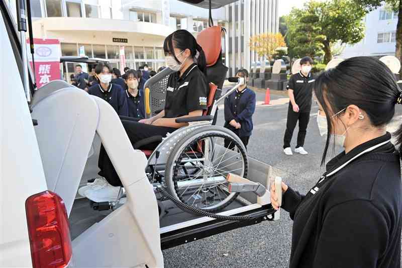 リフト付きの福祉車両を体験する城北高の生徒たち＝21日、山鹿市