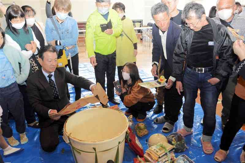 タイムカプセルを開封し、中に入れていた品物を取り出す山田小の卒業生ら＝23日、山江村