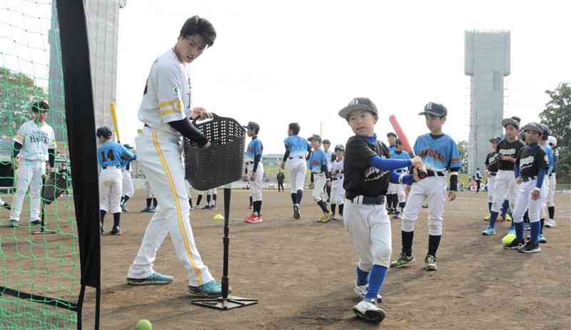 小学生に打撃を指導するソフトバンクの渡邉陸捕手（左）＝23日、熊本市中央区