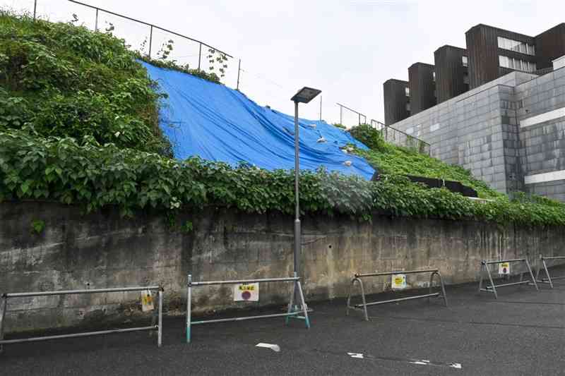 3月の大雨で表層が崩れたNHK跡地ののり面。右の建物は熊本県立美術館分館＝26日、熊本市中央区