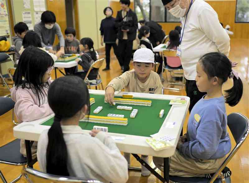 地域住民に見守られながら、マージャン卓を囲む子どもたち＝28日、荒尾市