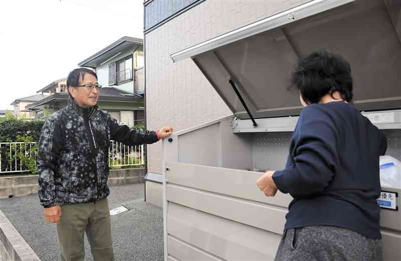 増設したごみステーションでのごみ捨てを見守る秋津校区第2町内自治会長の津田浩二さん（左）＝11月18日、熊本市東区