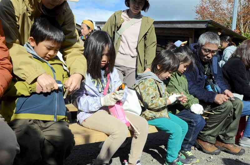 竹の棒を削って箸づくりをする子どもたち