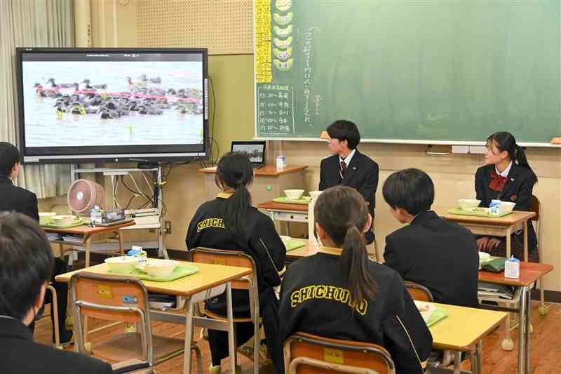 有機米を栽培方法を七城中の生徒に紹介する菊池農高の生徒（奥）＝11月29日、菊池市