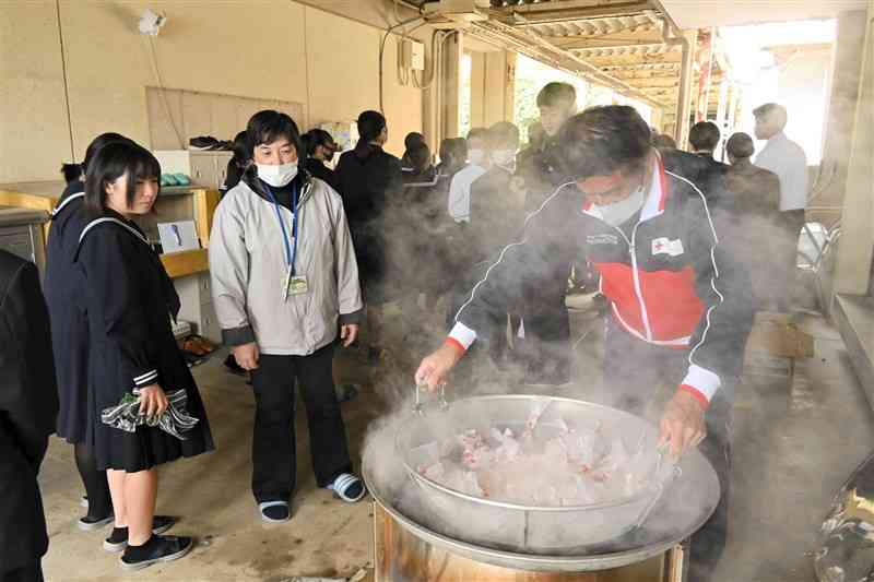 ボランティアからポリ袋に入れたコメを炊く方法を教わる生徒＝11月29日、菊池市