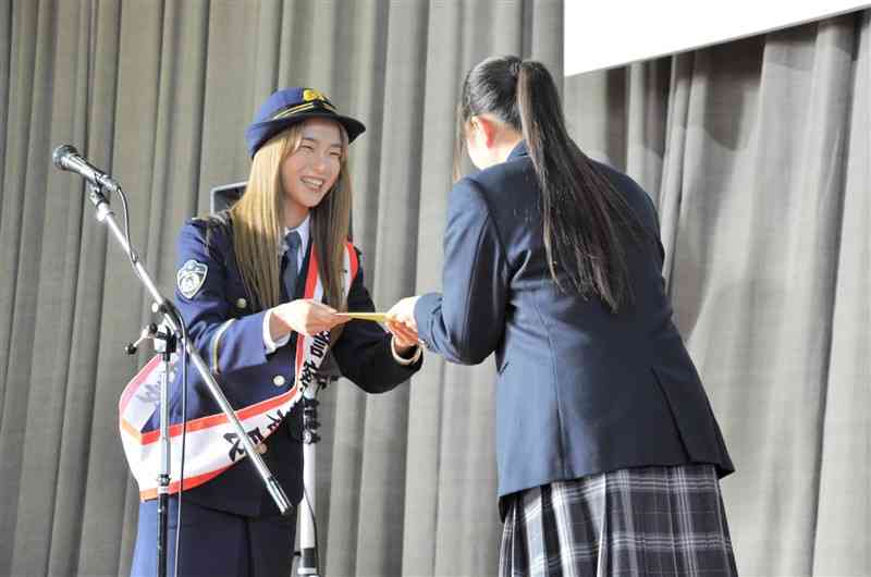 専大熊本高をサプライズ訪問し、情報メディア科の生徒にサインを手渡すLeolaさん（左）＝2日、玉名市