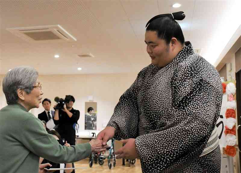 お年寄りたちから激励され、笑顔で握手に応じる琴桜＝熊本市東区