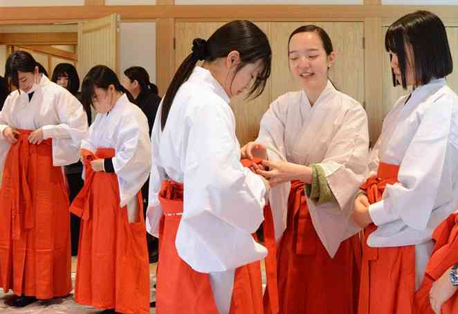 正月に向けて巫女の衣装合わせをする参加者＝8日、熊本市中央区