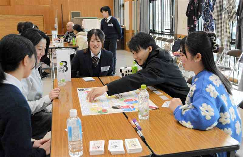 必由館高生が作ったすごろくを楽しむ参加者＝8日、熊本市中央区