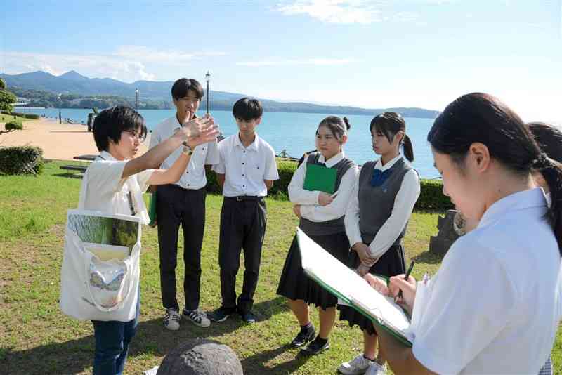 水俣湾埋め立て地で、高校生に解説する相思社職員（左端）＝10月、水俣市