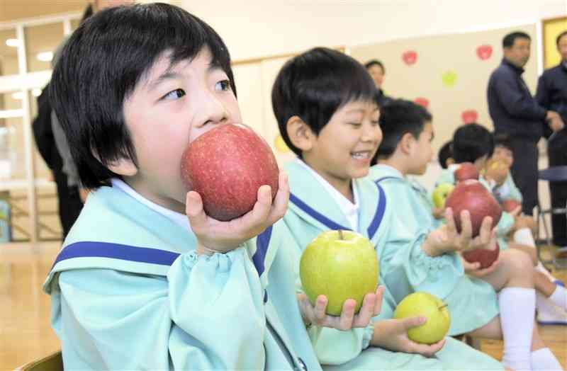 JA津軽みらいが贈ったリンゴを頰張る園児たち＝11日、熊本市西区