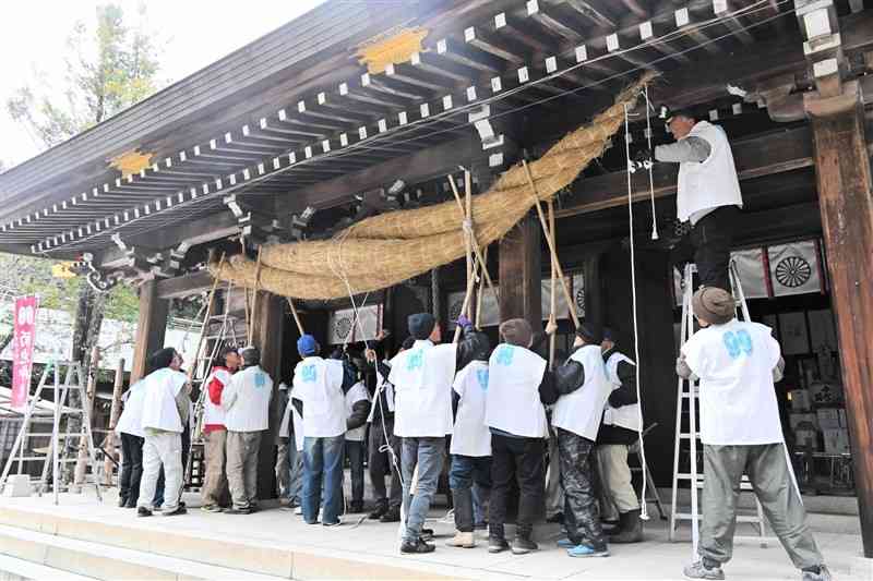 大しめ縄を拝殿に飾り付ける菊池神社の氏子ら＝15日、菊池市