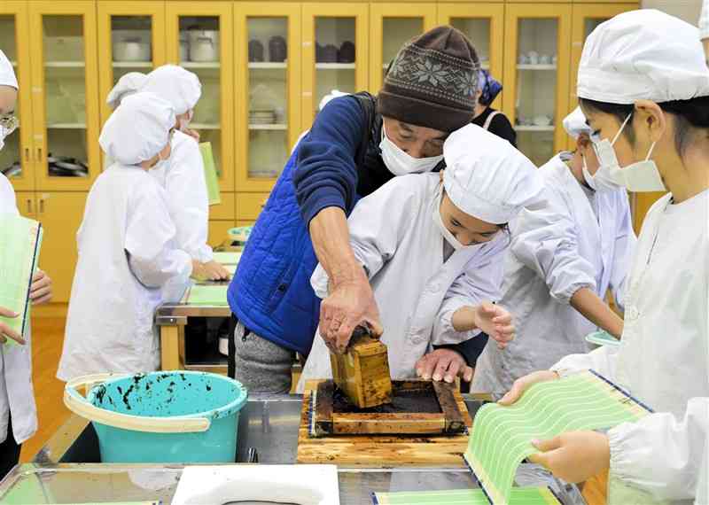 指導を受けながら木枠にノリを流し込む児童＝16日、長洲町