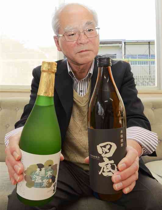 芋焼酎「田底」の原酒（右）と荒濾過を持つ田底地区活性化推進協議会の前田正男代表＝10日、熊本市北区