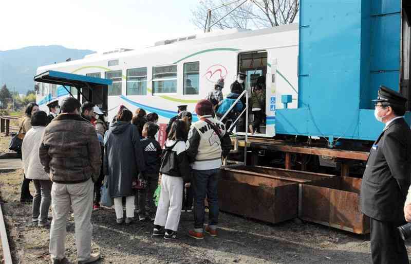 南阿蘇鉄道の列車に乗り込むくまTOMOサポーターと家族ら