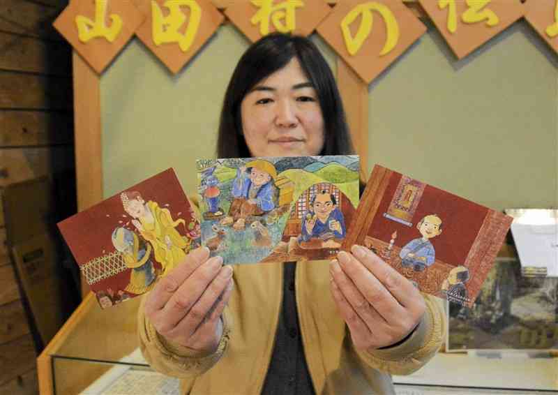 「山田伝助物語」を描いたポストカードを手にする小田美和さん＝18日、山江村