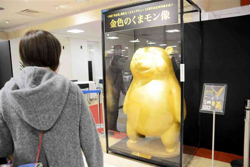 鶴屋百貨店で始まった「黄金展」の特別企画として展示された「金色のくまモン像」を見る買い物客＝19日、熊本市中央区