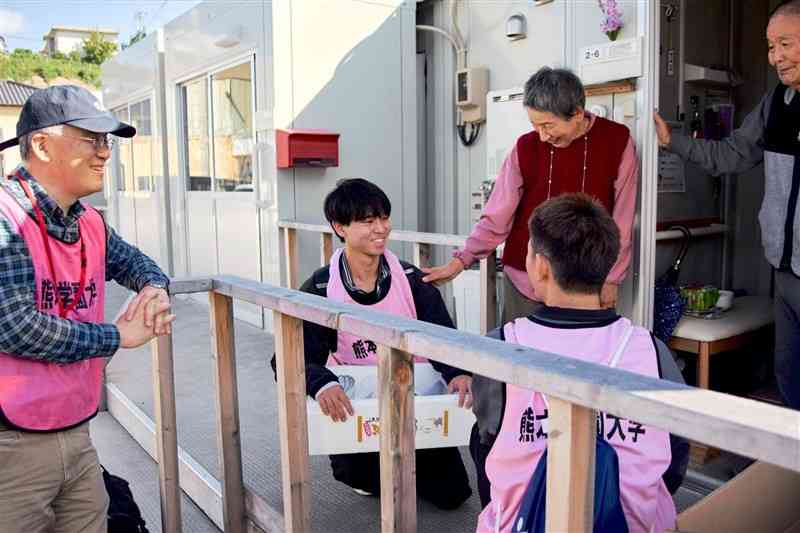 輪島市の仮設住宅で能登半島地震の被災者の話を聞く熊本学園大の学生や高林秀明教授（左端）＝11月末（高林教授提供）