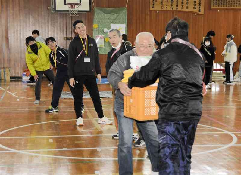 防災グッズを詰めたコンテナをリレーする参加者＝21日、球磨村