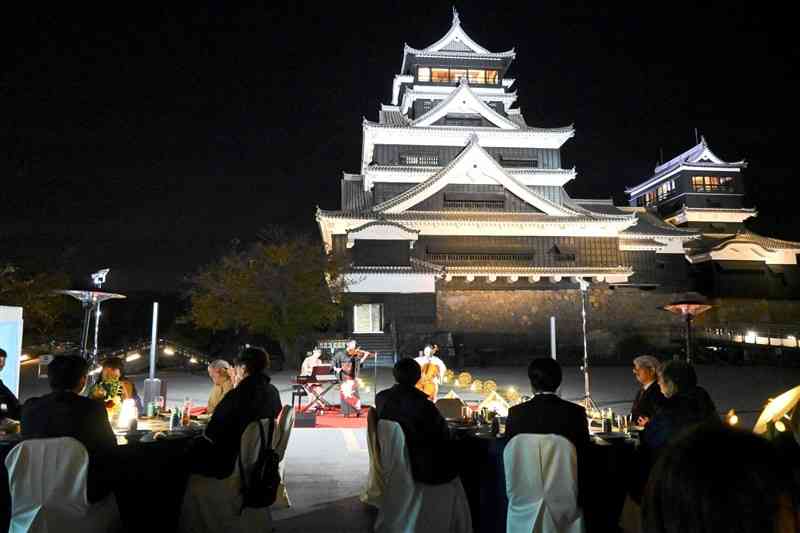 熊本城天守閣前広場であった「レセプション」。参加者はライトアップされた天守閣を前に飲食や楽器演奏などの演出を楽しんだ＝11月22日夜、熊本市中央区