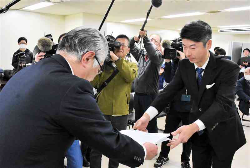 熊本市の深水政彦副市長（左）に条例制定請求書を提出する市民団体の西川文武代表＝25日、市役所