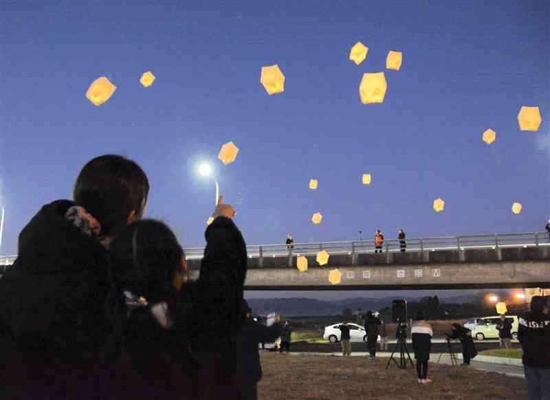 夜空に浮かぶランタンを見上げる参加者＝24日、熊本市北区