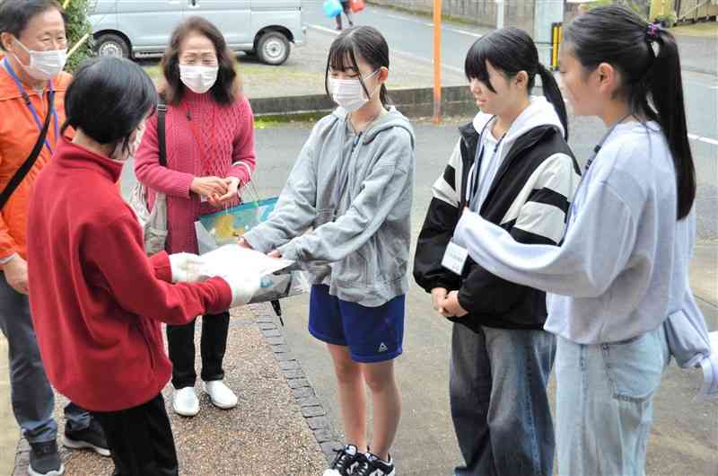 高齢者宅を訪れて声を掛け、マスクとカイロを手渡す「こども民生委員」の中学生（右）＝26日、御船町