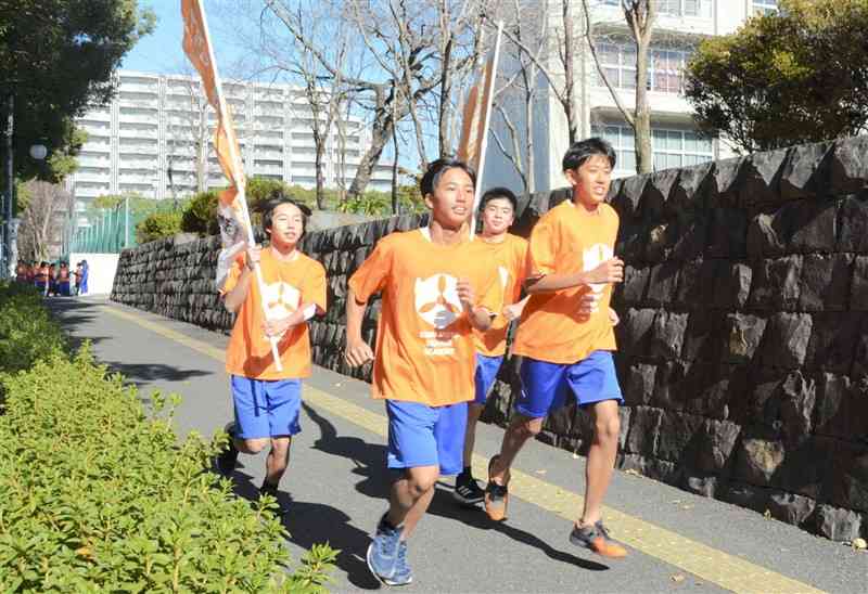 オレンジ色のTシャツを着て走る第二高の生徒たち＝24日、熊本市東区