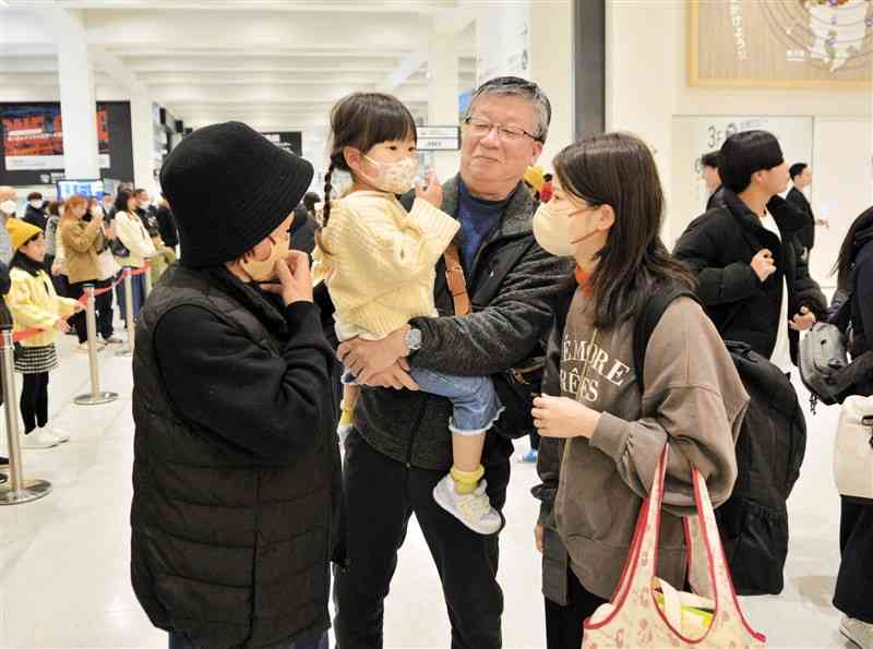 熊本空港の到着ゲートで祖父母の出迎えを受ける家族連れ＝28日、熊本空港