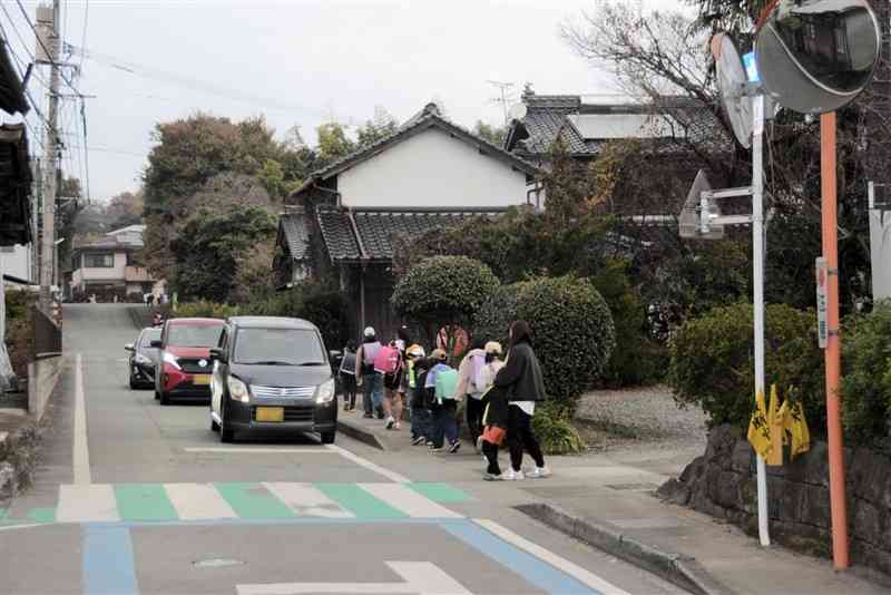 朝の一方通行が実現した道路。脇の歩道を通って、菊陽北小の児童らが登校している＝2024年12月12日、菊陽町（車のナンバーはぼかしてあります）